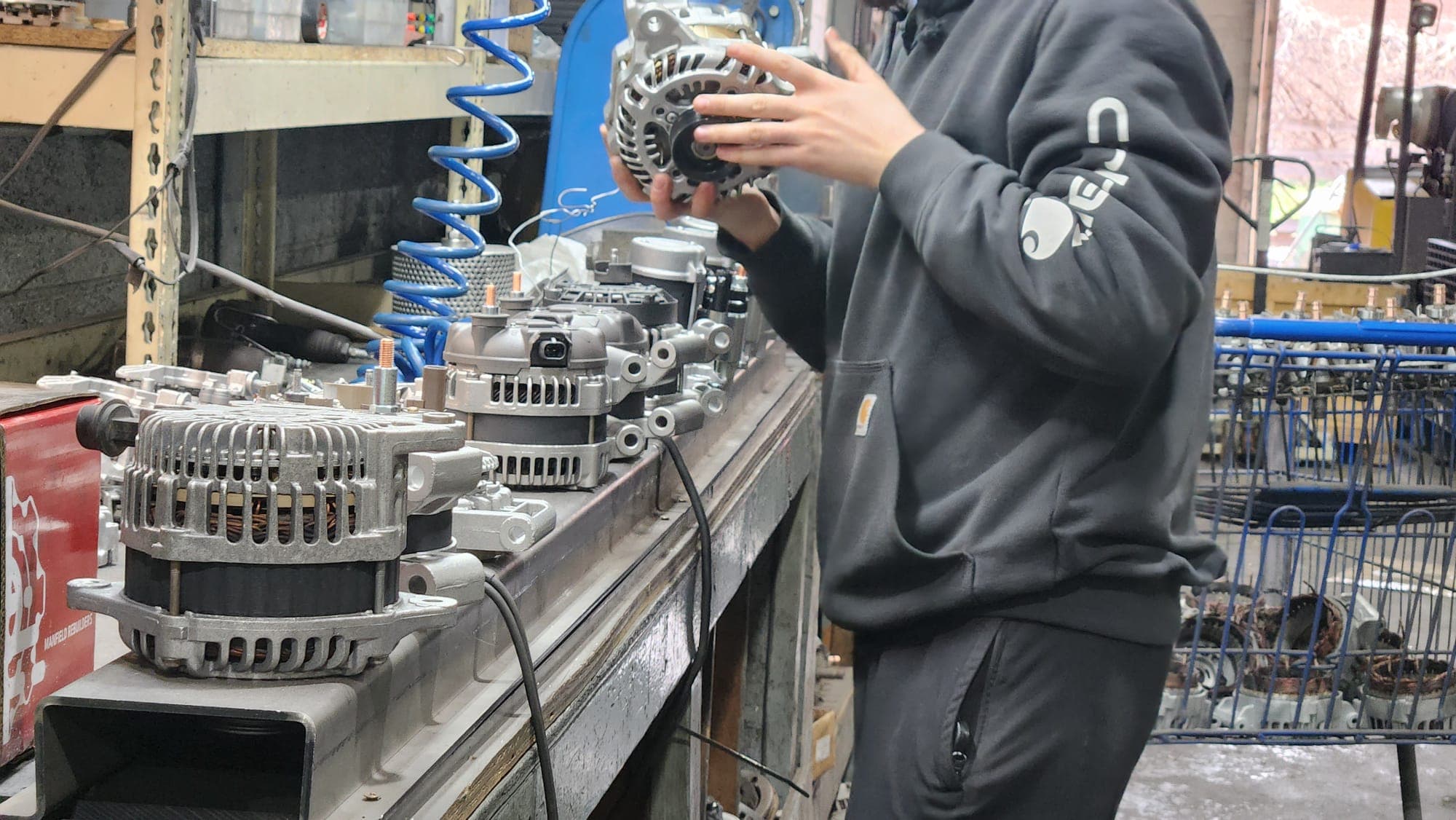 Rebuilt alternators and starters lined up on the bench at Manfield Rebuilders